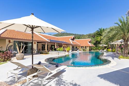 a pool at the resort with chairs and an umbrella at Villa Carlos, Luxury 7 BDR Private Pool Villa, Baan Bua Nai Harn, Phuket in Rawai Beach