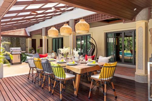 a dining table and chairs on a deck at Villa Carlos, Luxury 7 BDR Private Pool Villa, Baan Bua Nai Harn, Phuket in Rawai Beach