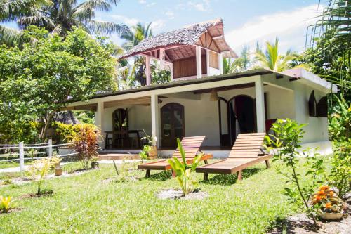 une petite maison avec deux chaises dans la cour dans l'établissement Analatsara Eco Lodge, sur l'île aux Nattes