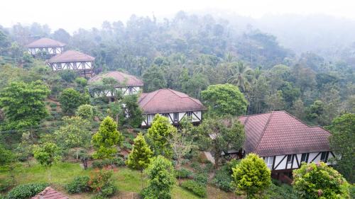 a group of houses on a hill with trees at Jeevess Retreat Wayanad in Wayanad
