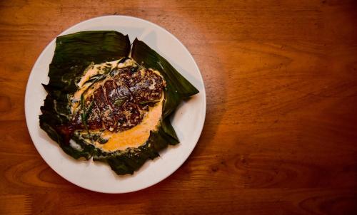 a plate of food on a wooden table at Kuruva Island Resort And Spa - By KABINI BREEZE in Mananthavady