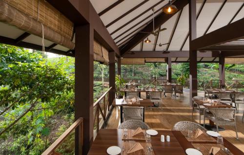 a restaurant with wooden tables and chairs and trees at Jeevess Retreat Wayanad in Wayanad