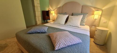 una camera da letto con un grande letto con due cuscini sopra di Villa Aigarden maison d'hôtes ad Avignone