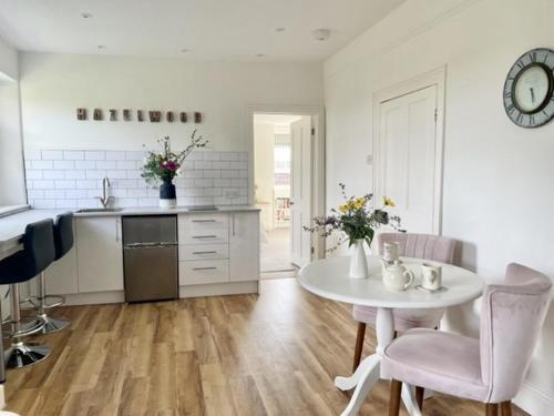 cocina blanca con mesa, sillas y encimera en The Mount Somerton Apartments - Somerset Private, Peaceful & 400 mtres from the village en Somerton