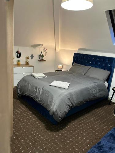 a bed with a blue headboard in a bedroom at Bv Comfy Attic Studio At Deighton Huddersfield in Huddersfield