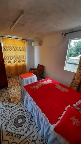 a bedroom with a red bed and a window at CHEZ MADAM ROSE in Le Morne