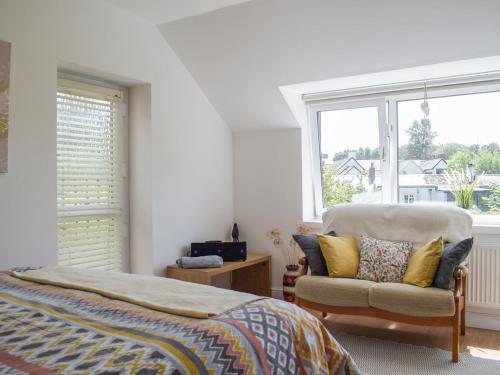 a bedroom with a bed and a chair and a window at Elizabeth House in Chirk