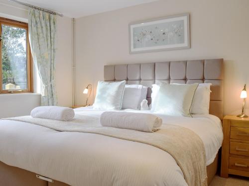 a bedroom with a large white bed with white pillows at The Lodge At Elmley Meadow in Little Comberton