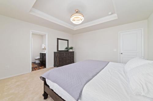 a white bedroom with a large bed and a mirror at N-E-G House - near DAVID WAYNE HOOKS Airport in Houston