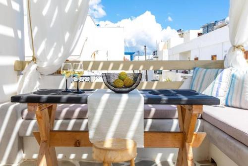 a table on a balcony with a glass of wine at Blue Heart Luxury Suites in Naxos Chora