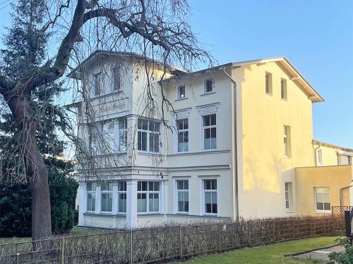 ein weißes und gelbes Haus mit einem Zaun in der Unterkunft Bansin, Villa an der Waldstraße in Bansin