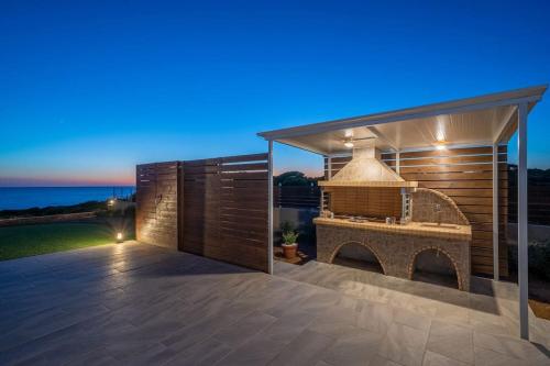a patio with an outdoor grill with the ocean in the background at Villa Kassiani in Svoronata