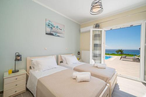 two beds in a bedroom with a view of the ocean at Villa Kassiani in Svoronata