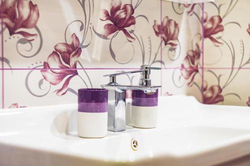 La salle de bains est pourvue d'un lavabo avec des fleurs violettes sur le mur. dans l'établissement KRISSTY Apartment, à Veliko Tarnovo