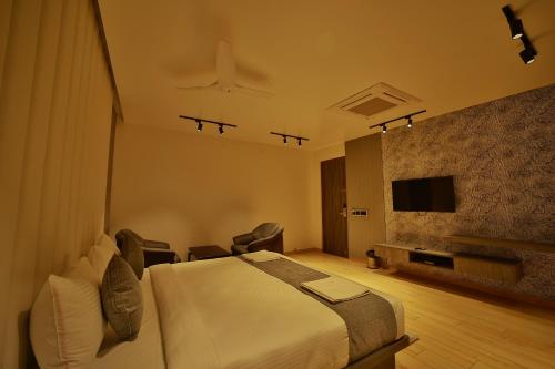 une chambre d'hôtel avec un lit et une télévision dans l'établissement The Mysore Grand, à Mysore