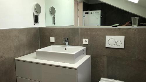 La salle de bains est pourvue d'un lavabo blanc et d'un miroir. dans l'établissement Ferienhaus OttoKeck, à Immenstadt