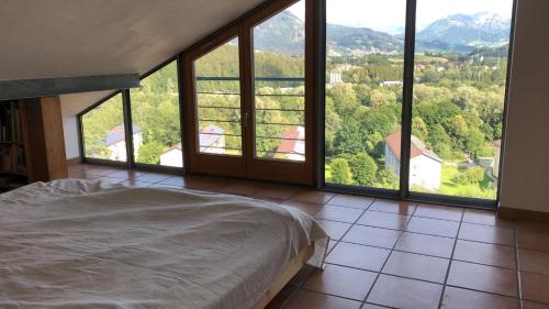- une chambre avec un lit et de grandes fenêtres avec vue dans l'établissement Ferienhaus OttoKeck, à Immenstadt