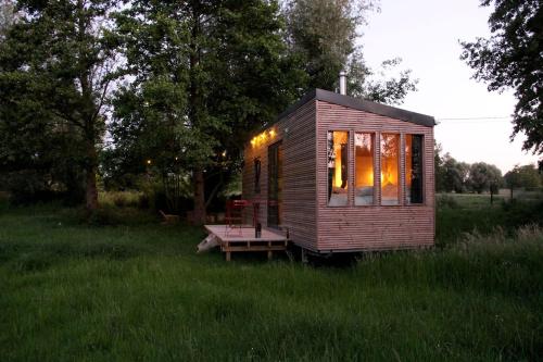 a tiny house with a picnic table in a field at Nice and Slow : Eco-responsible tiny house 