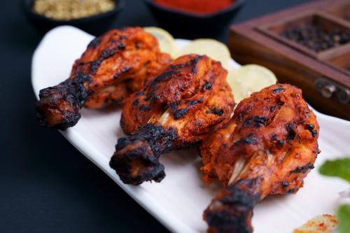 a plate of food with chicken wings and potatoes at Hotel Sifat International in Surat