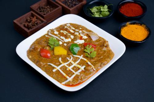 a white plate of food on a table with spices at Hotel Sifat International in Surat
