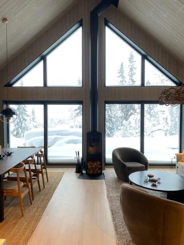 a living room with large windows and a table and chairs at Nybyggd 8-bäddars skidstuga i Lofsdalen in Lofsdalen