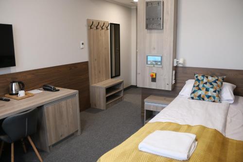 ein Hotelzimmer mit einem Bett, einem Schreibtisch und einem TV in der Unterkunft Centralny Ośrodek Sportu - Spała in Spała