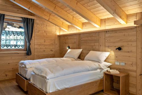 two beds in a room with wooden walls at Luxury Apartment Majon de Rita in Vigo di Fassa