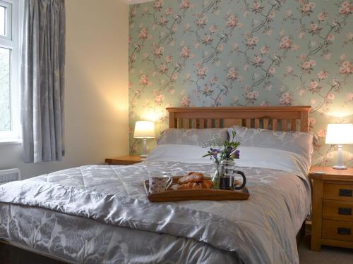 a bed with a tray of bread and flowers on it at Browney Cottage in Broadwood