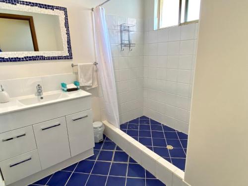 a bathroom with a sink and a shower with blue tiles at Forrest Holiday Unit Bunbury in Glen Iris