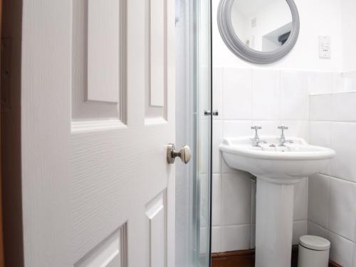 een witte badkamer met een wastafel en een spiegel bij Primrose Cottage in Ironbridge