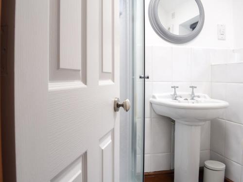 a white bathroom with a sink and a mirror at Primrose Cottage in Ironbridge