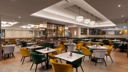 a dining room with tables and yellow chairs at Holiday Inn London Gatwick - Worth by IHG in Crawley