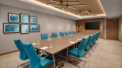 a conference room with a long table and blue chairs at Holiday Inn London Gatwick - Worth by IHG in Crawley