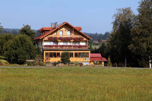 a large house with flowers on the front of a field at Pension Wiesengrund in Neuschönau