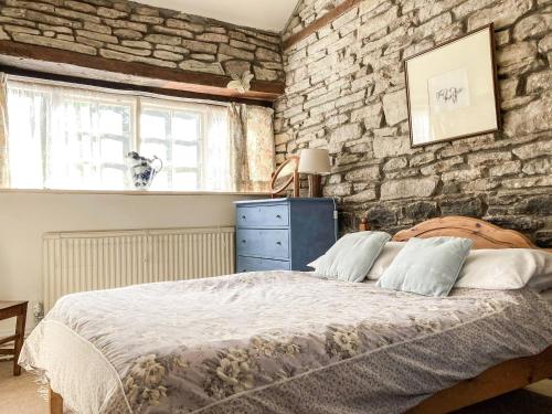 a bedroom with a bed and a brick wall at Stable Cottage in Abergavenny