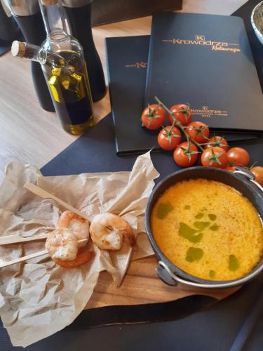 a bowl of soup and some shrimp on a cutting board at Krowodrza Centrum Konferencyjno - Hotelowe in Kraków