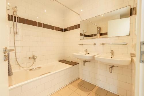 La salle de bains est pourvue de 2 lavabos, d'une baignoire et d'un miroir. dans l'établissement Seinpaal, à Callantsoog