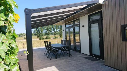 a patio with a table and chairs on a deck at Cube IJsselzicht in Lathum
