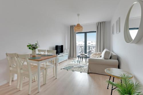 Downtown Apartments Riverside Dwie Motławy في غدانسك: غرفة معيشة بيضاء مع طاولة وأريكة