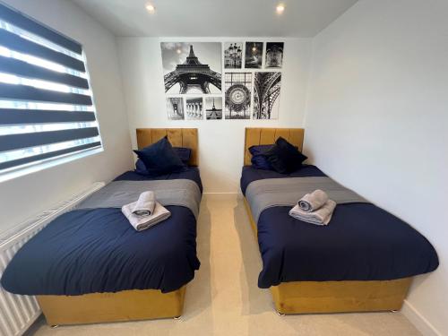 two beds in a room with blue pillows at Star London Station Road 3-Bed Haven in London