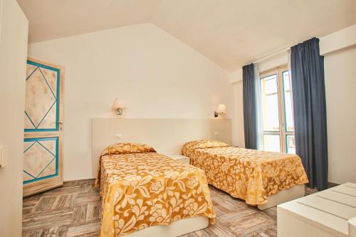 a bedroom with two beds and a window at Hotel Muita di Mari in Santa Teresa Gallura