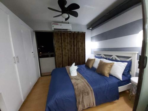 a bedroom with a blue bed with a ceiling fan at Ri's One Oasis w Free Pool back of SM City Mall in Davao City