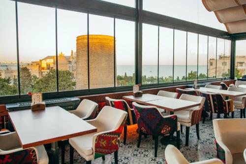 un restaurante con mesas, sillas y ventanas grandes en Sultan Inn Boutique Hotel en Baku