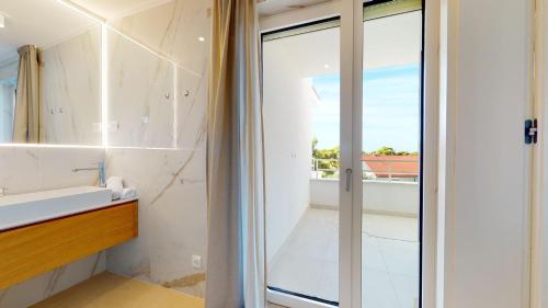 a bathroom with a glass door leading to a balcony at Villa Zoe Suites in Komiža