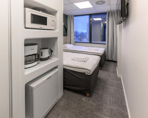 a small room with two beds and a microwave at GreenStar Hotel Oulu in Oulu