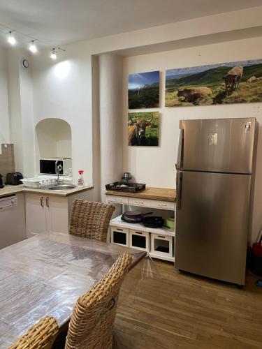 een keuken met een roestvrijstalen koelkast en een tafel bij LE LOFT et le T2, Le Mont Dore, au pied de La Dordogne in Le Mont-Dore