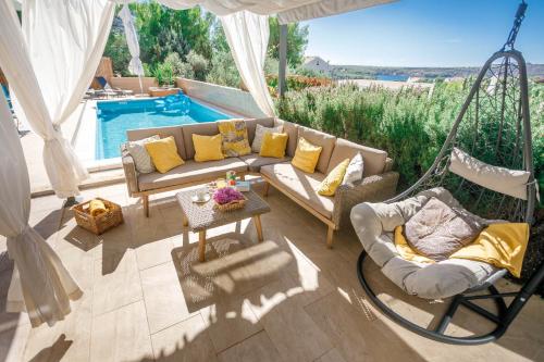 a patio with a couch and chairs and a swing at Villa NONO Jure - Private Pool & Jacuzzi, Milna Brač in Milna