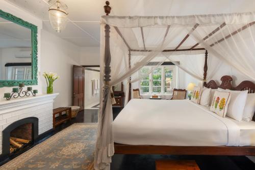 een slaapkamer met een hemelbed en een open haard bij Highgrove Estate in Labugolla