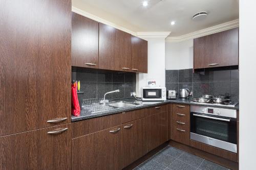 a kitchen with wooden cabinets and a sink at Sanctum Maida Vale in London