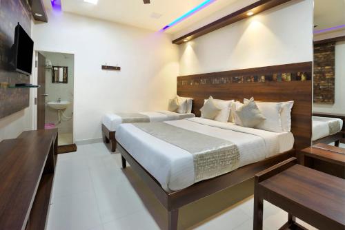 a hotel room with two beds and a bathroom at Mannars Deluxe Lodge in Mysore